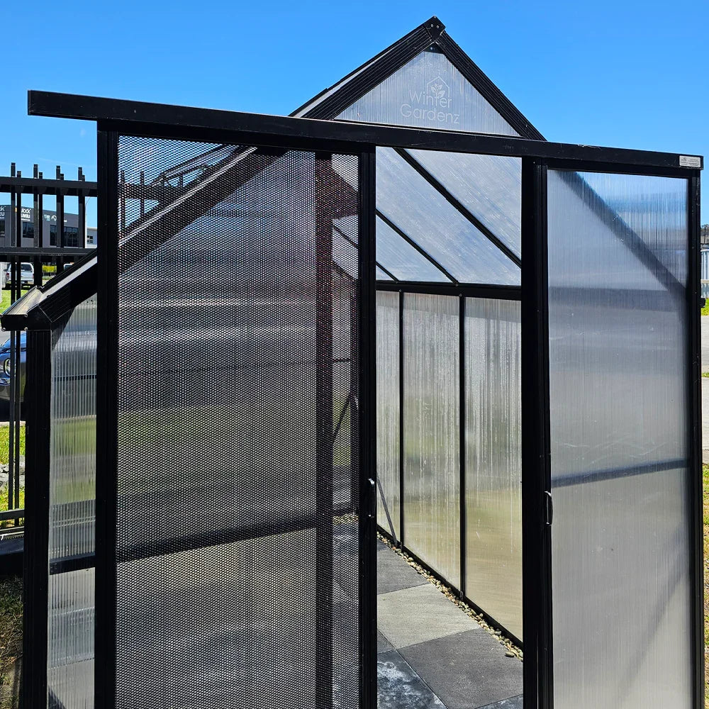 Black framed entrance with screendoor and extended door track on translucent greenhouse panels