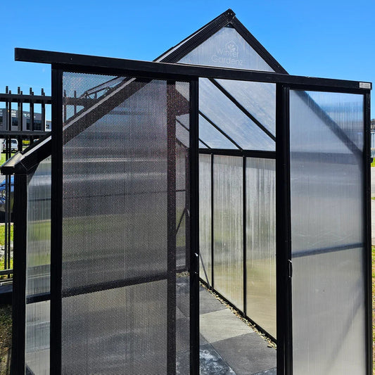 Black framed entrance with screendoor and extended door track on translucent greenhouse panels